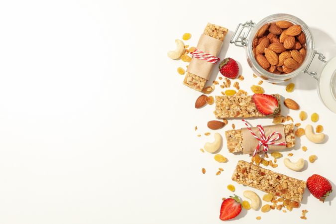 Granola bars, strawberry and almond on plain background, top view