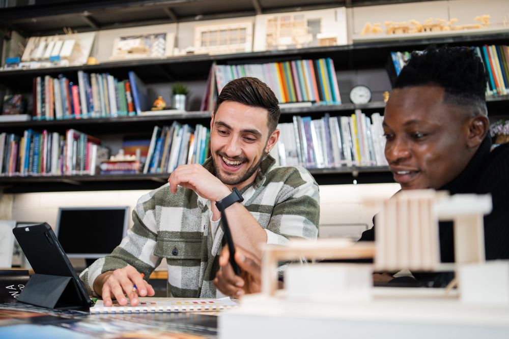 Two happy male colleagues working on design project in office