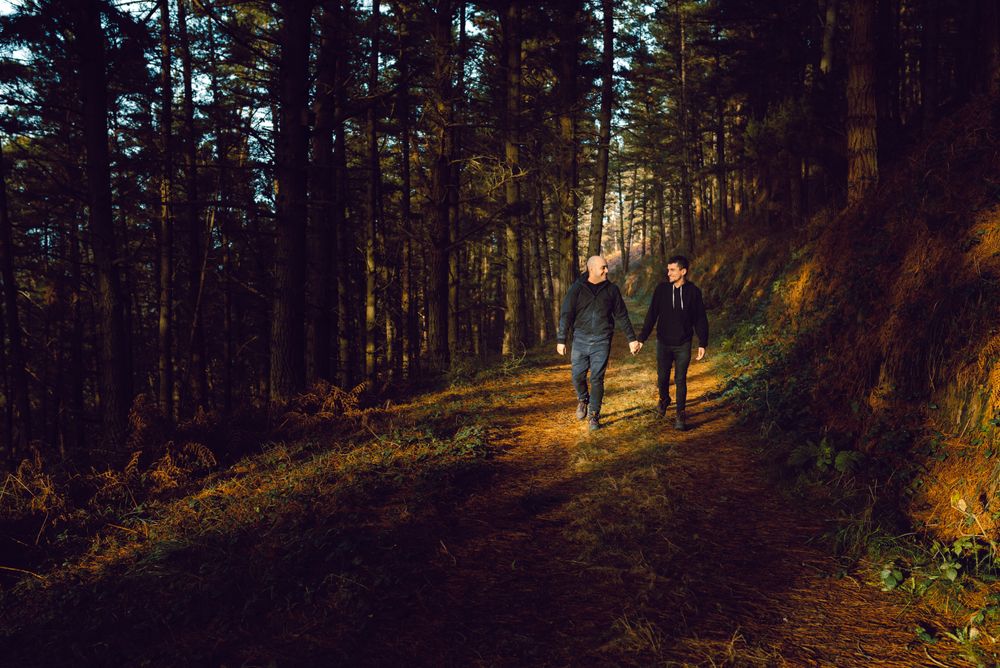 Men holding hands and walking in forest