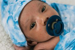 Newborn baby wrapped on soft blanket with pacifier