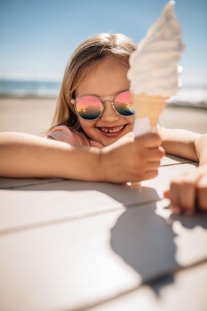 Beautiful girl holding a ice cream over a beach boardwalk