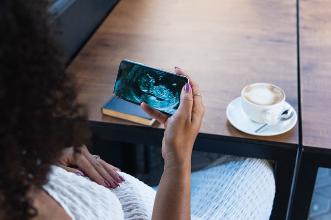 Black woman watching baby ultrasound picture on smartphone