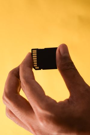 Hand holding SD card in yellow studio shoot