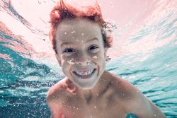 Cheerful boy swimming underwater in pool