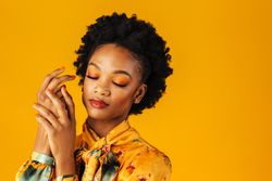 Elegant Black woman holding her hands to her face with her eyes closed