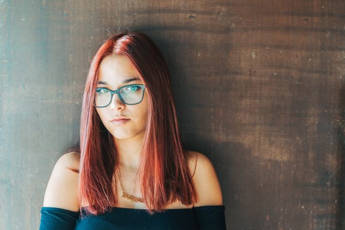 Woman in glasses leaning on wall