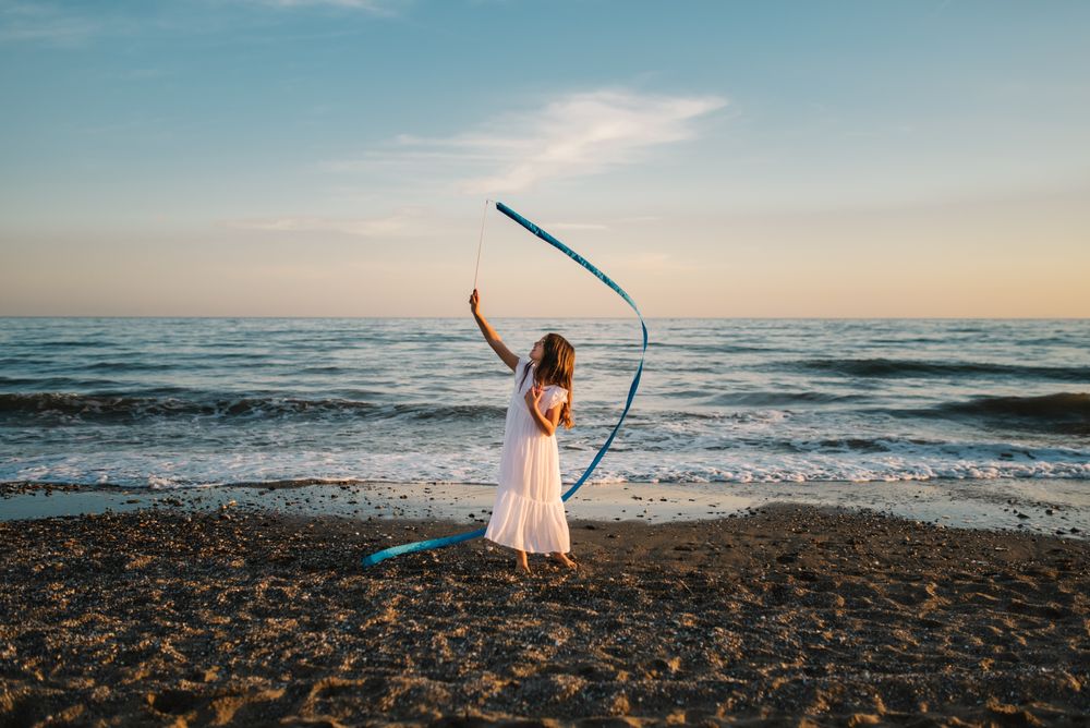 Adorable girl playing with ribbon on seaside