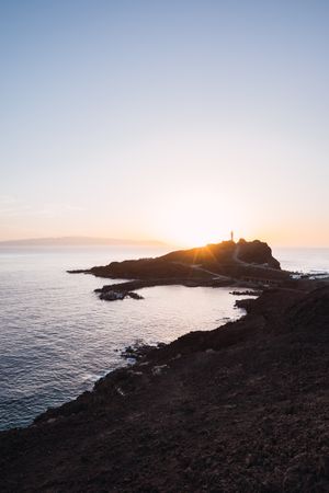 Picturesque sunset beams above cliff on seaside