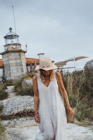 Woman in hat standing against beacon on seashore