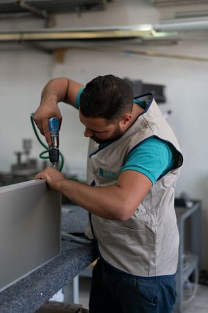 Man drilling through a window panel at a factory