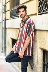 Portrait of serious dark haired man leaning on wall outside