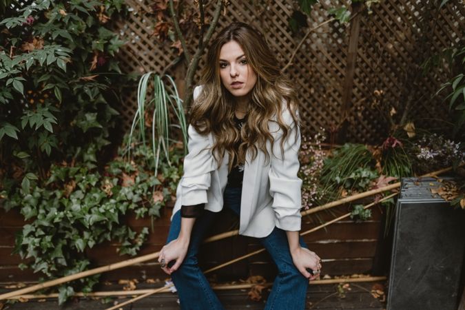 Woman sitting on planter in garden