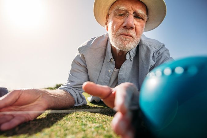 Man checking the distance between a boules and the jack to know the result