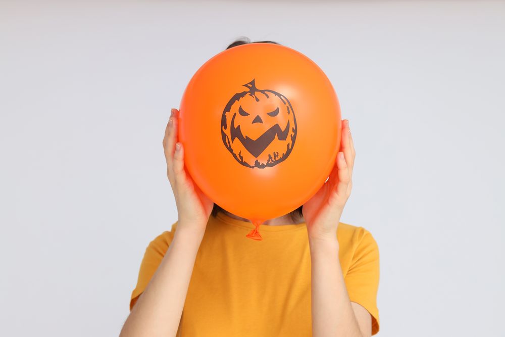Concept of Halloween, Woman holds Halloween balloon on light background