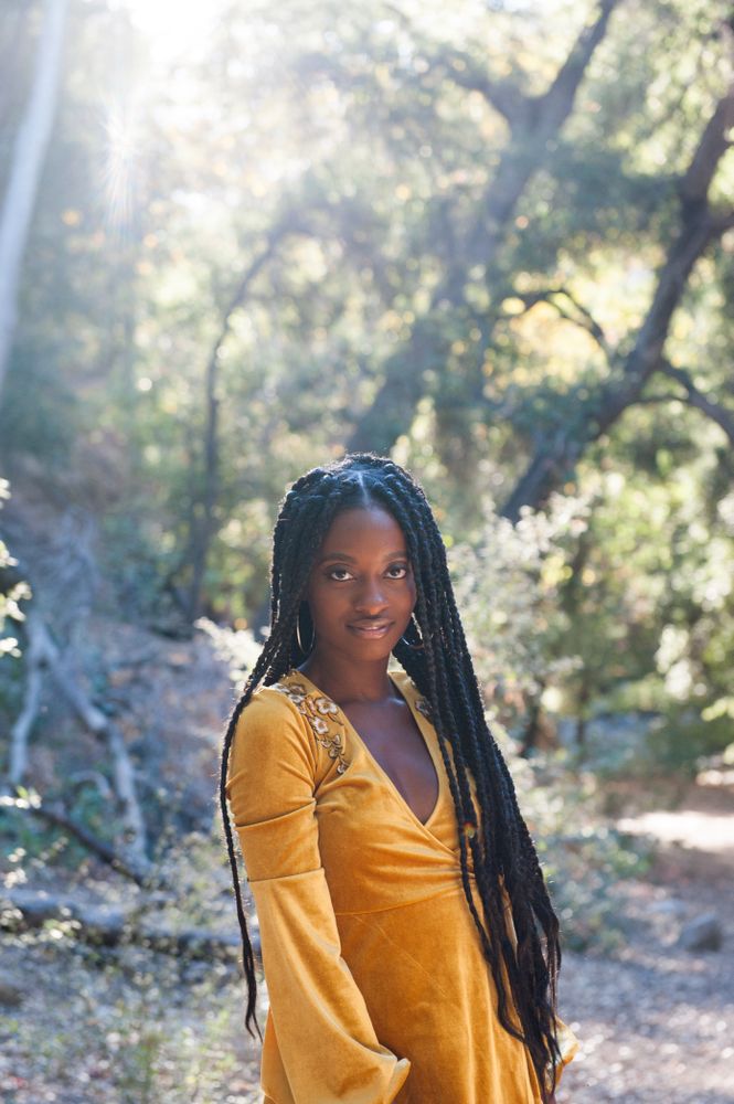 Portrait of a woman in front of trees with the sun behind