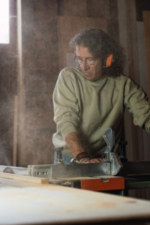 Carpenter cutting wood with circular saw in joinery