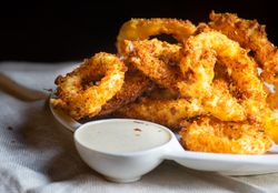 Plate of onion rings on table with dip