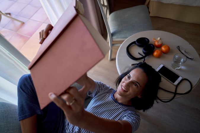 Hispanic woman reading book in room