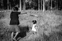 Grayscale photo of a mother holding a wooden stick and walking with her daughter in the woods 5lwga0