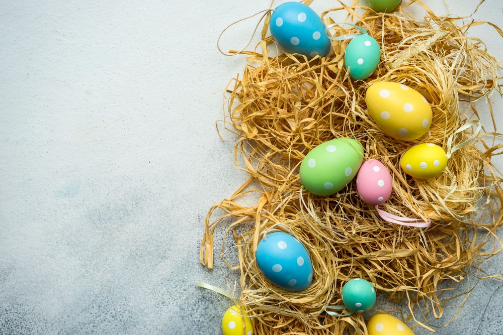 Easter card concept with pastel decorations scattered on straw