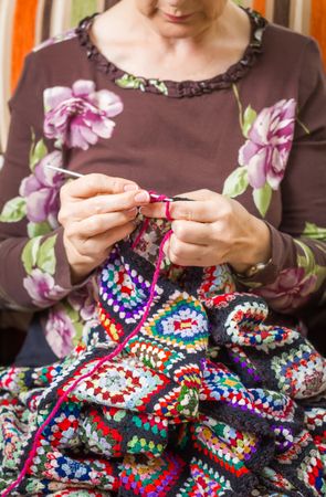 Hands of woman knitting a vintage wool quilt