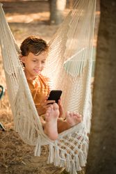 Boy using smartphone in hammock