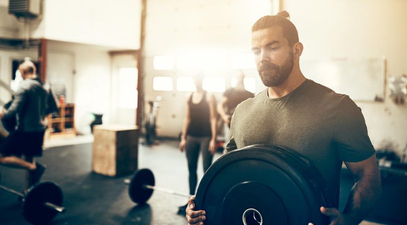 Man moving weights in busy gym