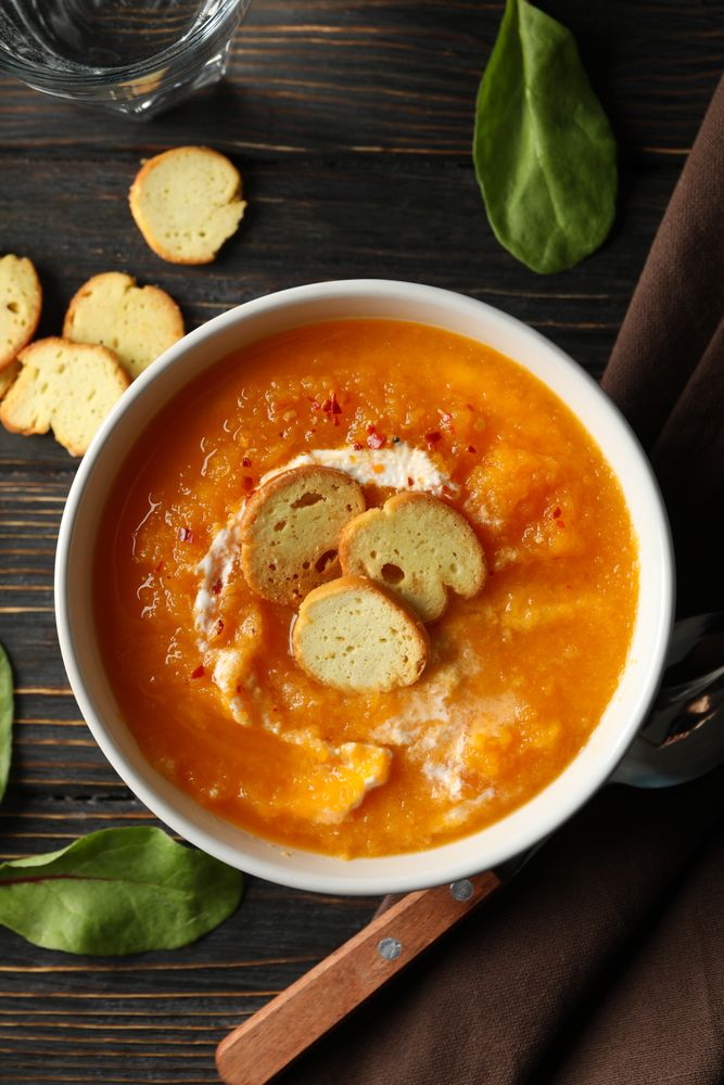 Bowl of delicious pumpkin soup on table, vertical composition