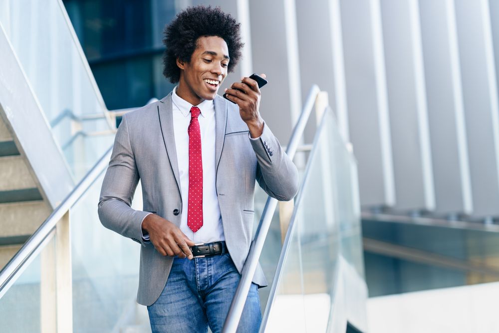 Smiling man in business casual on stairs speaking on his phone