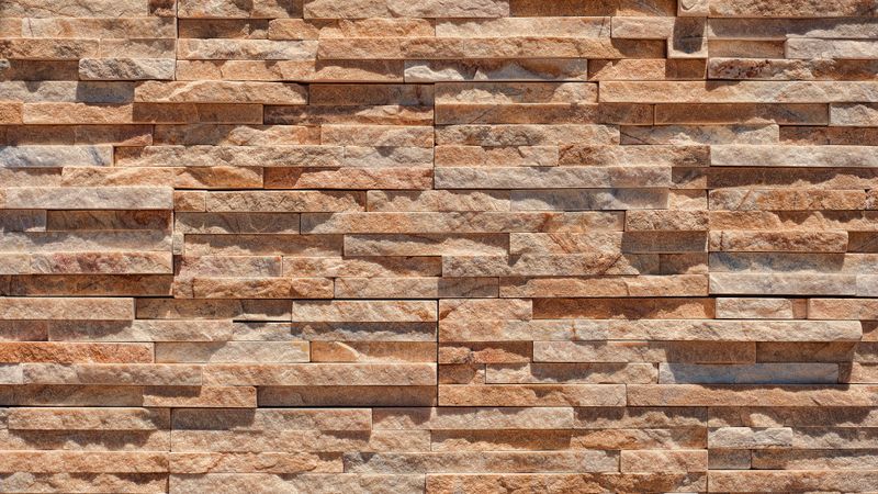 Horizontal sandstone brick wall with warm orange and beige stone texture