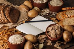 Wholegrain food empty notebook and freshly baked rye bread on table