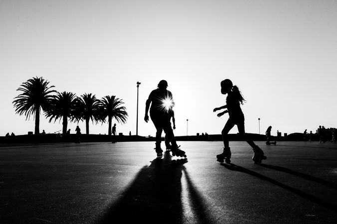 Silhouette of two people skating on the coast