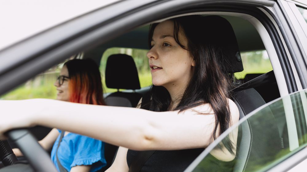 Two people happily travel by car, one of them driving, during a weekend getaway