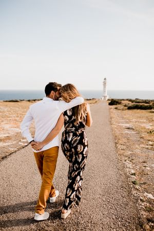 Smiling lovers cuddling on path to sea