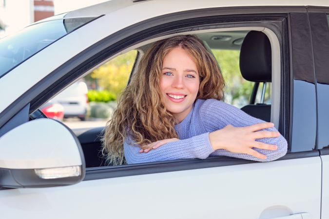 Gorgeous smiling woman sitting in car on sunny street