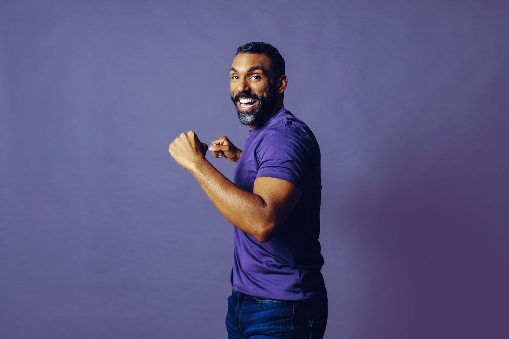 Happy male flexing turning around in purple studio, copy space