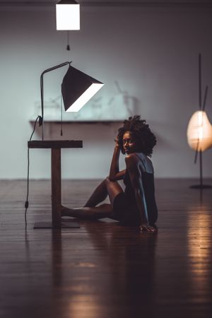 Woman in dress sitting on floor beside lamps indoor