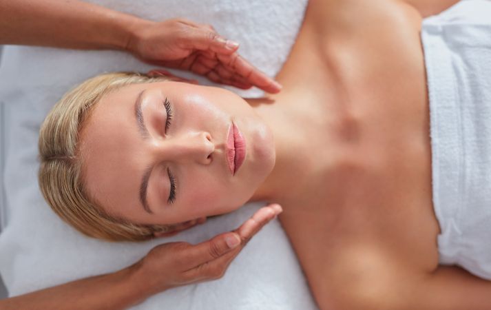 Blonde woman lying back receiving facial treatment