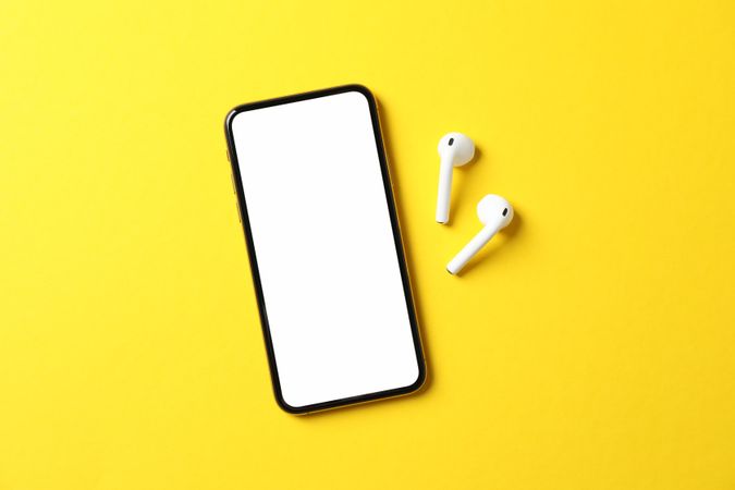 Phone with empty screen on yellow background, top view