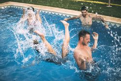 Friends jumping in pool and swimming
