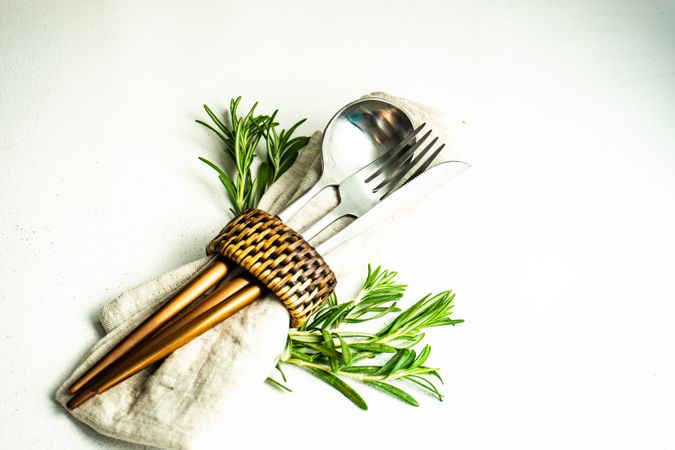 Cutlery set wrapped with napkin and fresh rosemary sprig