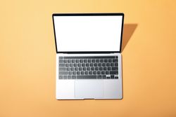 Top view of laptop with mockup screen on light orange desk