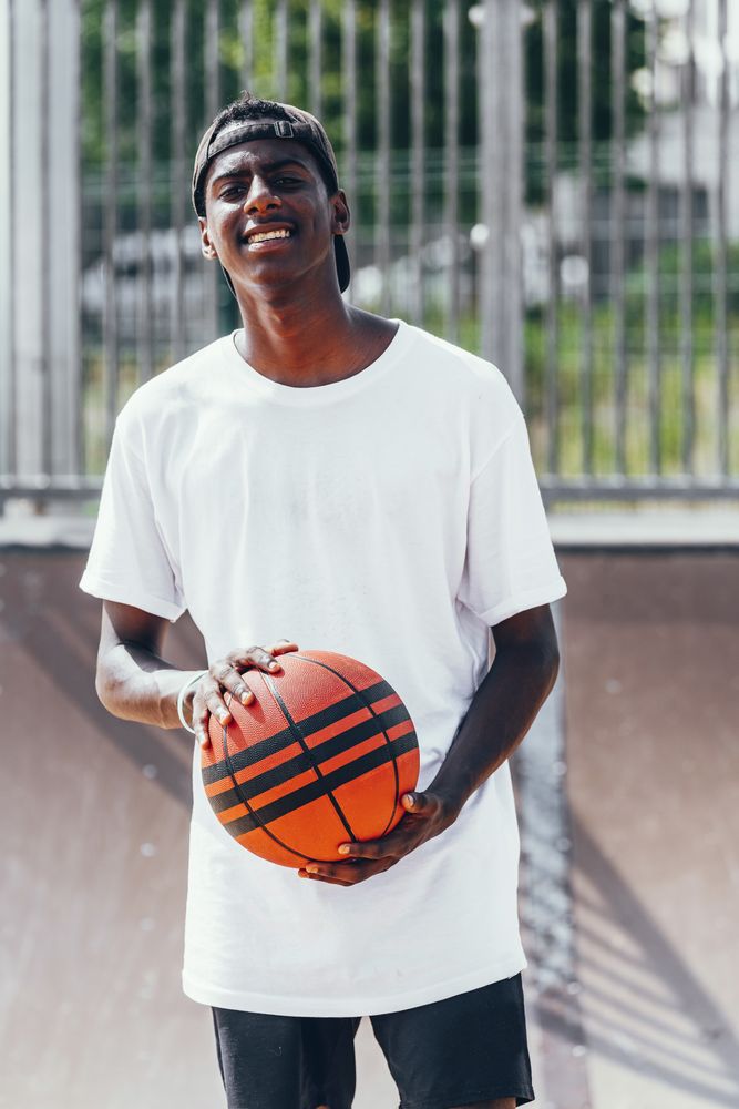 Black sportsmen with ball smiling and looking at camera