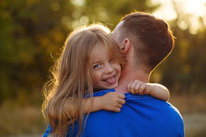 Smiling girl hugging her dad in blue