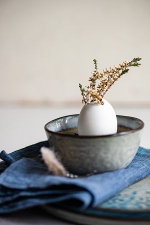 Side view of decorative egg with plant and feather on Easter table setting