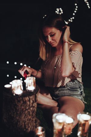 Woman lighting candles in dark garden