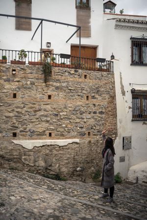 Asian female on aged cobblestone steps in city alley