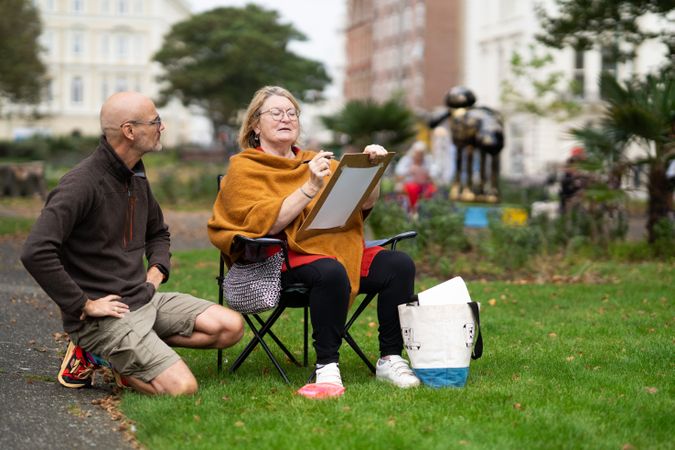 Woman sitting in park with art instructor