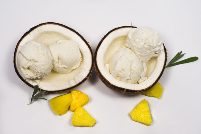 Top view of two coconut halves with delicious ice cream and pineapple fruit chunks