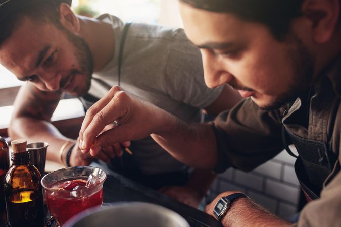 Two bartenders creating new recipes for cocktails